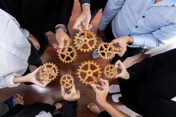 Group of multiracial business people joining gear wheels together as effective unity and productive teamwork concept. Efficient system business team process for solution solving. Meticulous