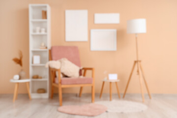 Blurred view of stylish living room with paintings, armchair and lamp