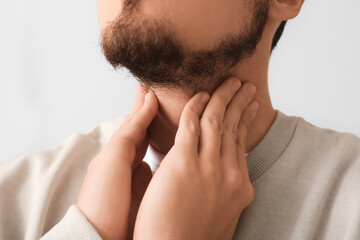 Young man with thyroid gland problem on grey background, closeup