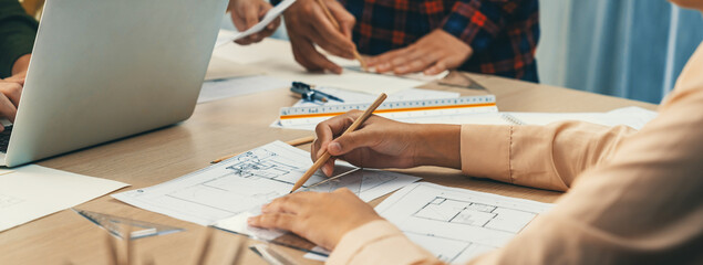 Professional architect drawing blueprint during meeting at modern architectural office on table with architectural document and stationary scatter around. Blurring background. Closeup. Delineation - Powered by Adobe