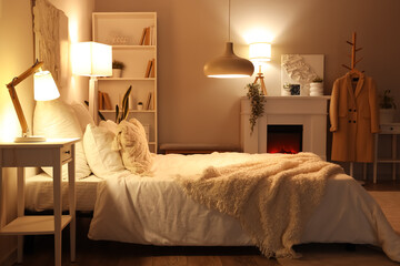 Interior of cozy bedroom with soft blankets on comfortable bed and glowing lamps at night