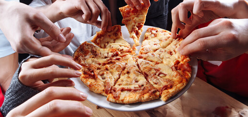 eating pizza with a group of people, fast food pizza with cheese, ketchup and meat. Hands of people...
