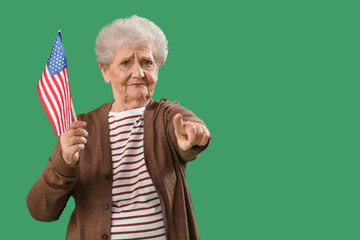 Senior woman with USA flag pointing at viewer on green background. Accusation concept