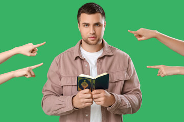 People pointing at young man with Koran on green background. Accusation concept