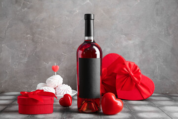 Bottle of wine with gifts, zephyr and decor on grey tile table against grunge background....