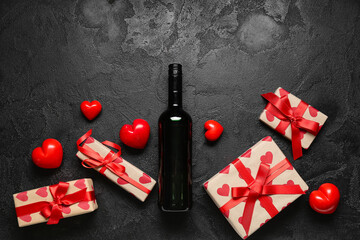 Bottle of wine with gifts and hearts decor on black grunge background. Valentine's Day celebration