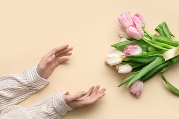 Female hands with bouquet of beautiful tulips on yellow background. International Women's Day
