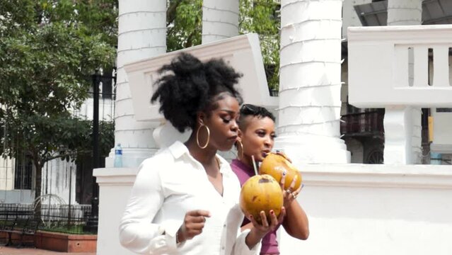 Latin American women having fun in the city drinking coconuts