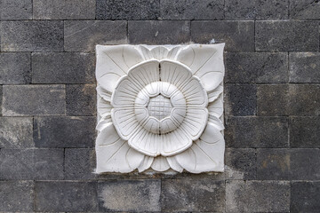 Balinese stone carved flower pattern background on brick stone wall