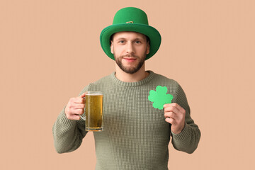 Young man in leprechaun hat with glass of beer and clover on brown background. St. Patrick's Day...