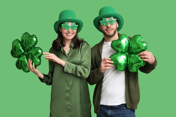 Beautiful young couple in leprechaun hats and decorative glasses with air balloons in shape of...