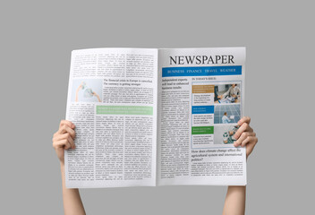Woman with newspaper on grey background