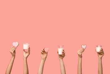 Women with heart-shaped cookies and glasses of milk on pink background. Valentine's Day celebration