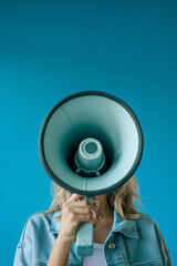 woman speaking in to a megaphone on a blue background 