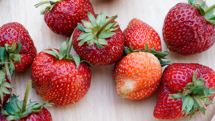 Strawberry fruit in a wooden cup placed on a wooden table.