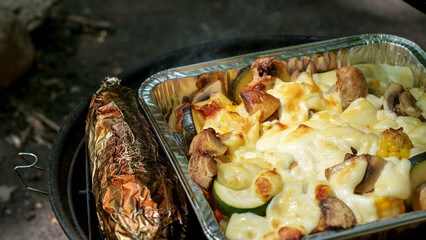 Grilled vegetables and corn on stainless BBQ grill with flames on dark background. Food and cuisine concept.