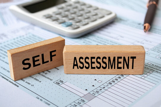 Self assessment text on wooden blocks with tax form and calculator background. Taxation concept