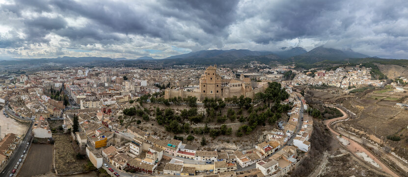 Aerial view of Caravaca de la Cruz castle dominating the landscape with square and circular towers, medieval palace and Baroque ornament facade church