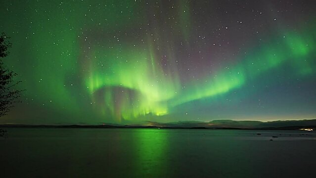 A majestic display of aurora borealis above the mirrorlike surface of the fjord.