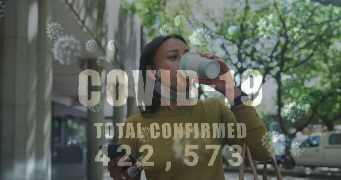 Covid-19 text with increasing numbers against woman drinking coffee and using smartphone