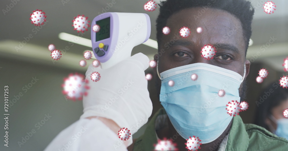 Poster image of covid-19 cells floating with man having temperature checked wearing face masks