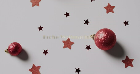 Obraz premium Red Christmas ornaments lie among scattered stars on a surface