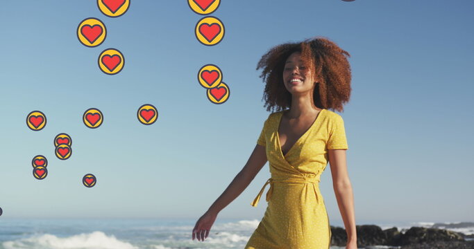 Image of heart digital icons over woman dancing on beach