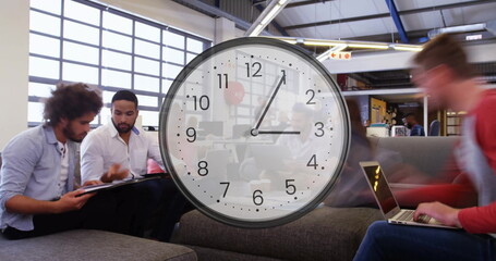 Image of clock ticking over diverse business people in office