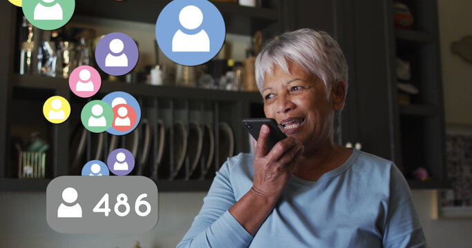 Multiple profile icons floating against african american senior woman talking on smartphone at home