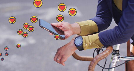 Multiple heart icons floating against mid section of woman with bicycle using smartphone - Powered by Adobe