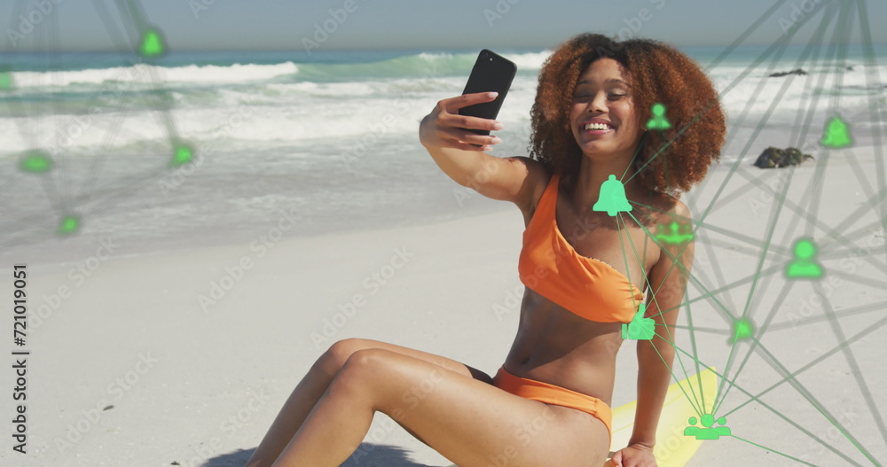 Poster image of networks with digital icons over woman taking selfie with smartphone on beach