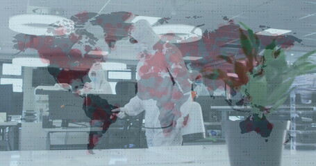 Image of world map turning red with man disinfecting the office