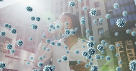 Covid-19 cells floating against african american woman with lowered face mask drinking coffee