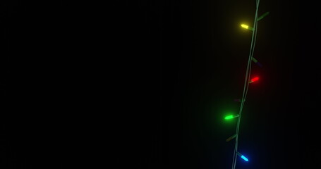 Strand of coloured christmas string lights flashing on black background, copy space