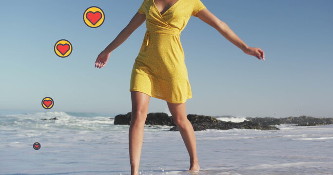Image of heart digital icons over woman dancing on beach