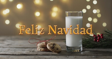 Feliz navidad text in orange over christmas cookies and milk and bokeh lights background