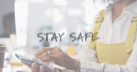 Obraz premium Image of flashing words with woman disinfecting smartphone in office wearing face masks