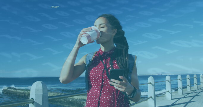 Image of floating numbers over woman drinking coffee and using smartphone on promenade