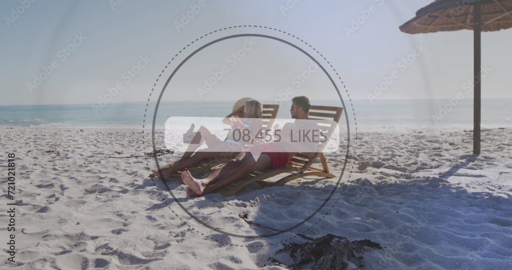 Poster image of speech bubble with likes text and numbers over couple in deckchairs on beach