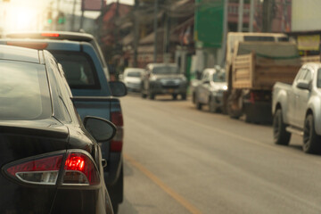 Rear side of black car with turn on brake light. Stop in line at an intersection with traffic lights on asphalt road. Various cars were lined up along the side of the city road.