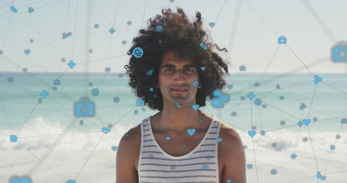 Image of network of digital icons over happy man smiling on beach