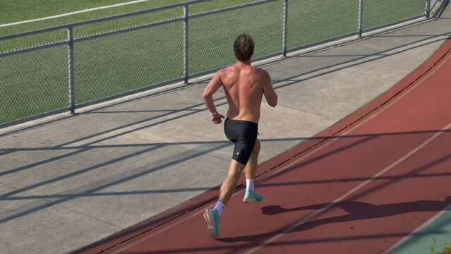 Man Athlete Jogging At The Stadium In The Morning - Tracking Shot