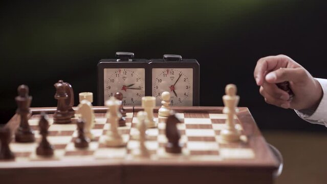 Professional chess game with time clock in the background.
