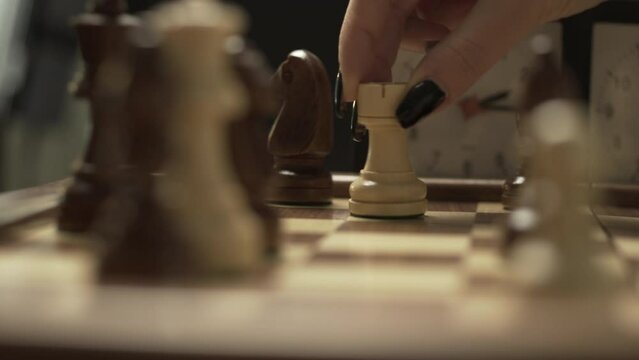 Close up shot of Wood chessboard during game. Woman plays wooden chess. Person makes move in chess game. Concept of successful business woman, strategic thinking.