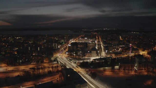 Aerial view of cars driving on the snowy roads between the illuminated buildings of Vaasa, Finland