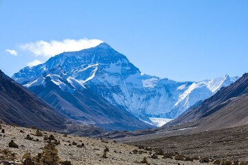 Capture the awe-inspiring grandeur of Mt. Everest as its majestic pyramid shape dominates the horizon, seen from the serene surroundings of the North Everest Base Camp in Tibet. 