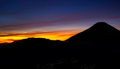 Morning sun reflecting golden sky over Sindoro and Sumbing mountains in Central Java, Indonesia