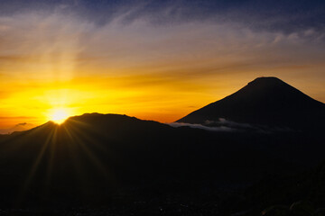 Golden sunrise from behind Sindoro and Sumbing mountains in Central Java, Indonesia
