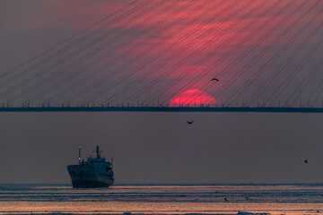 Winter Vladivostok. Russian bridge at dawn. A bright red sun rises behind the bridge. Eastern...