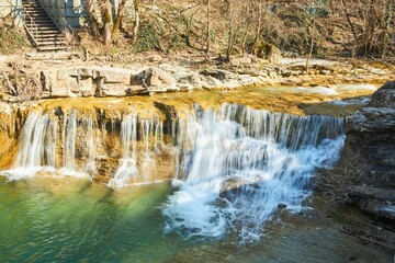 A waterfall in nature in early spring. Landscape of forest and mountain river